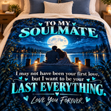 A bed with a printed comforter or blanket featuring a romantic night scene: two people sitting on a dock by a lake under a large full moon, with the text 'TO MY SOULMATE' and a sentimental message below in bright teal and white lettering.