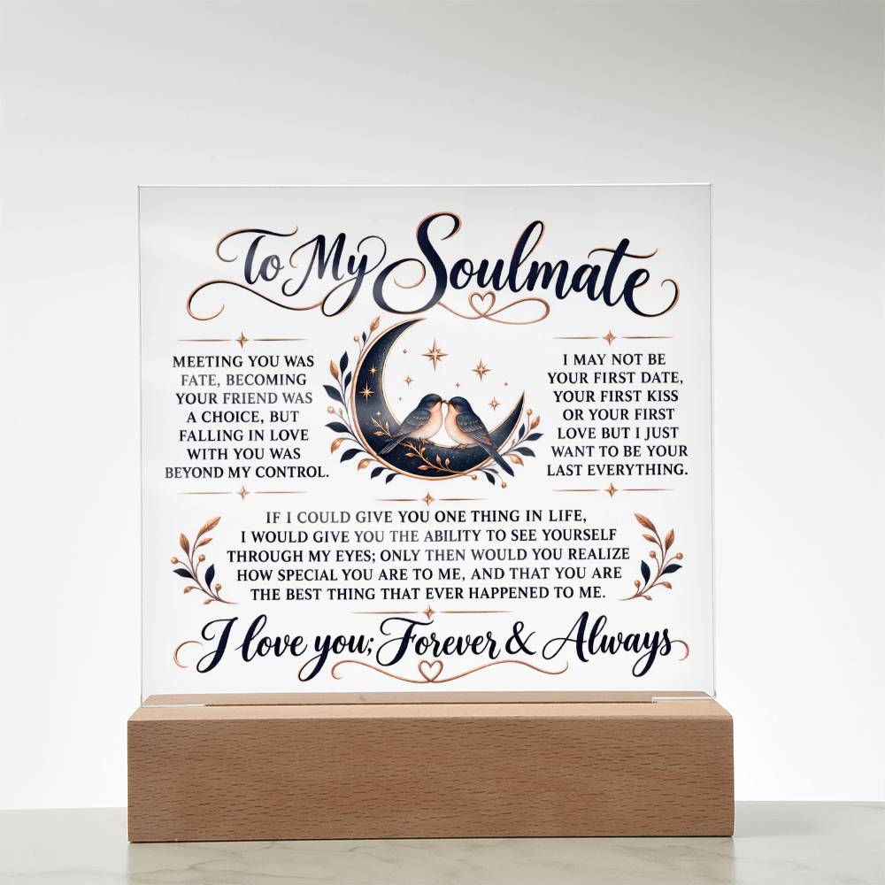 A square white acrylic or glass plaque on a light wood base, featuring romantic text addressed 'To My Soulmate' with a central illustration of a couple under a crescent moon and small floral accents.