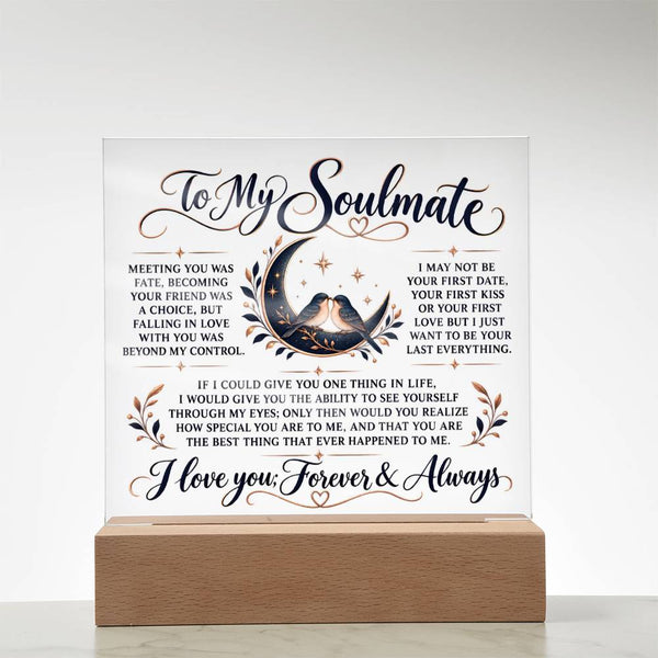 A square white acrylic or glass plaque on a light wood base, featuring romantic text addressed 'To My Soulmate' with a central illustration of a couple under a crescent moon and small floral accents.