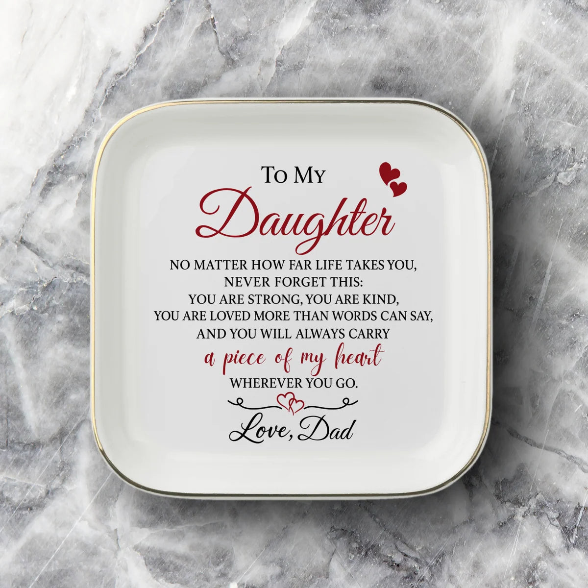 A square white ceramic plate with rounded corners, featuring black printed text and a heart graphic that reads 'difference maker' on a gray and white marble background.